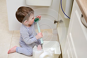 A child is playing with chemical cleaning products under the sink in the