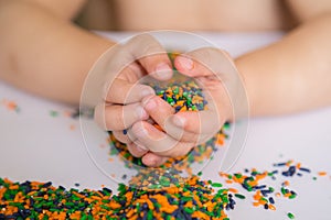 Child playing with colored rice.