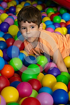 Child playing with colorful balls in playground ball pool. Activity toys for little kid. Kids happiness emotion having fun in ball