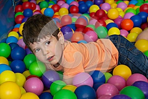 Child playing with colorful balls in playground ball pool. Activity toys for little kid. Kids happiness emotion having fun in ball