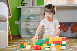 Child playing with colorful toy blocks. Little boy building tower at home or day care. Educational toys for young children.