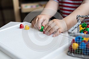 Child playing with colorful toys sitting at a window. Little boy