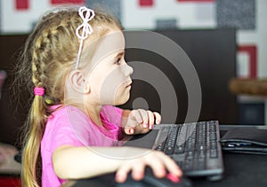 A child playing on the computer. Happy little girl playing video game pc