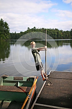 Child Playing on Dock by Fishing Row Boat on Small Lake in Northern Woods