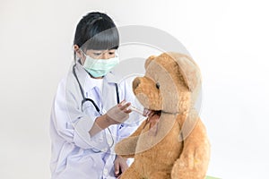 Child playing doctor with stethoscope and teddy bear