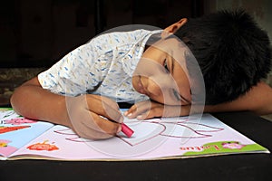 Child is playing with drawing books. Child coloring. Thoughtful expression.