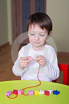 Child playing with educational toys beading