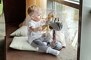 Child playing with a fan by the window