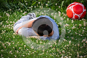 Child playing football. One Asian boy falling down