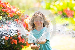 Child playing in garden, pours from the hose, makes a rain. Happy childhood concept.