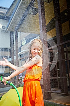 Child playing with garden sprinkler. Summer outdoor water fun in backyard. Ggirl play with hose watering grass. Kid