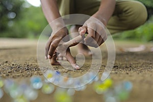 A child playing with glass marbles which is an old Indian village game. Glass Marbles are also called as Kancha in Hindi Language