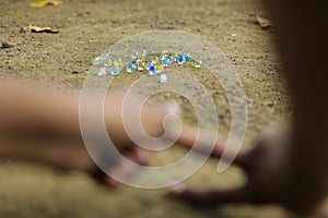 A child playing with glass marbles which is an old Indian village game. Glass Marbles are also called as Kancha in Hindi Language