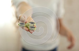 Child playing with green fidget spinner closeup in bright room