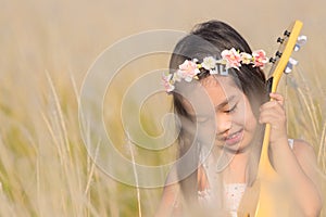 Child playing guitar to meadow in nature on sunny day