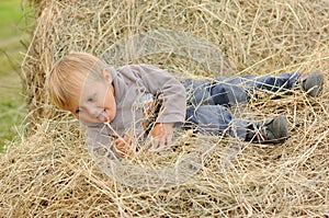 Child playing in hay pile