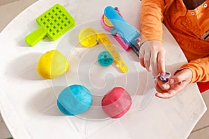 Child playing a home made playdough. Yellow, orande and pink modelling clay made at home