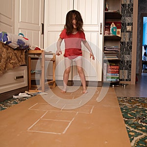 Child playing hopscotch inside at her home healthy body lifestyle concept, side view. what to do in quarantine. street