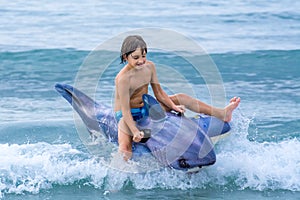 Child playing with inflatable shark in waves