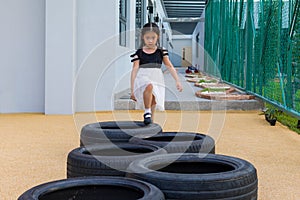 Child Playing Jumping Tires in Playground