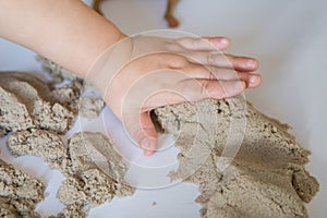 Child playing with kinetic sand. Baby`s sensory experiences