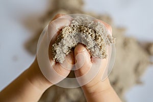 Child playing with kinetic sand. Baby`s sensory experiences photo
