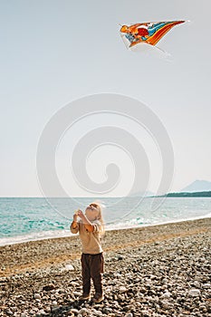 Child playing with kite flying outdoor walking on beach summer vacations