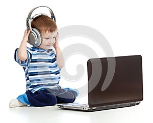 Child playing laptop listen to music in headphones