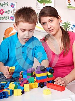 Child playing lego block with mother at home.
