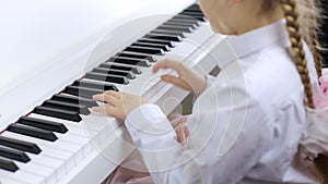 Child playing music on a white piano. The concept of playing a musical instrument