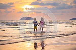 Child playing on ocean beach. Kid at sunset sea