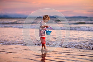 Child playing on ocean beach. Kid at sunset sea