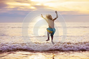 Child playing on ocean beach. Kid at sunset sea