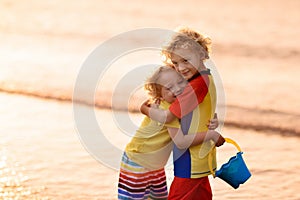 Child playing on ocean beach. Kid at sunset sea