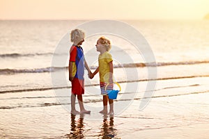 Child playing on ocean beach. Kid at sunset sea