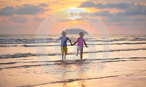 Child playing on ocean beach. Kid at sunset sea