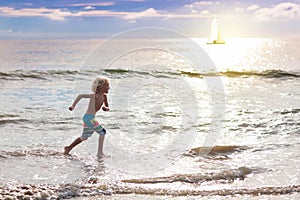 Child playing on ocean beach. Kid at sunset sea