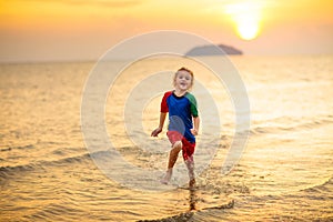 Child playing on ocean beach. Kid at sunset sea