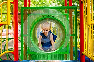 Child playing on outdoor playground. Little baby girl plays on school or kindergarten yard. Active kid on colorful swing