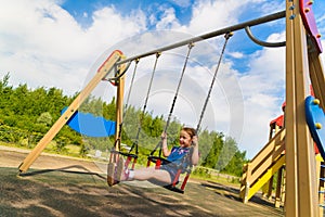 Child playing on outdoor playground in rain. Kids play on school or kindergarten yard. Active kid on colorful swing. Healthy