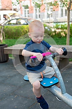 Child playing on outdoor playground in summer. Kids play on kindergarten yard. Active kid holding swing and a pink scoop