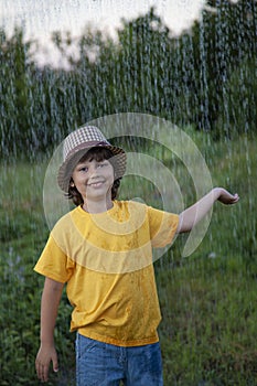 Child playing outdoor on rainy day. Happy boy in summer rain