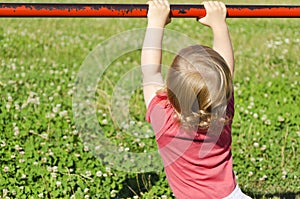 Child playing in a park grabbing a railing