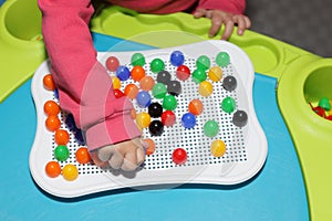 Child playing plastic colored toy mosaic on the table