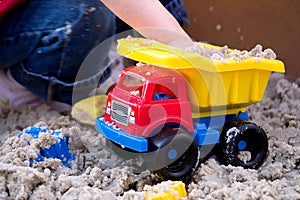 Child Playing with Plastic Truck in Sand