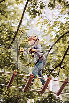 Child playing on the playground. Cute school child boy enjoying a sunny day in a climbing adventure activity park. Happy