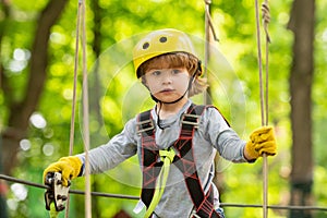 Child playing on the playground. Happy little child climbing on a rope playground outdoor. Adventure climbing high wire