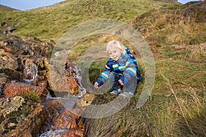 Child playing on a pond in geothermal area in Krysuvik on early sunny morning, Southern Peninsula Reykjanesskagi, Reykjanes