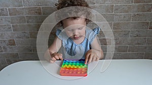Child Playing Poppit Fidget Toy. Young Little Girl At Home Holding Pop It New Fidget Toy