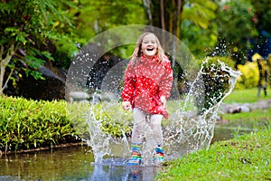 Child playing in puddle. Kids jump in autumn rain